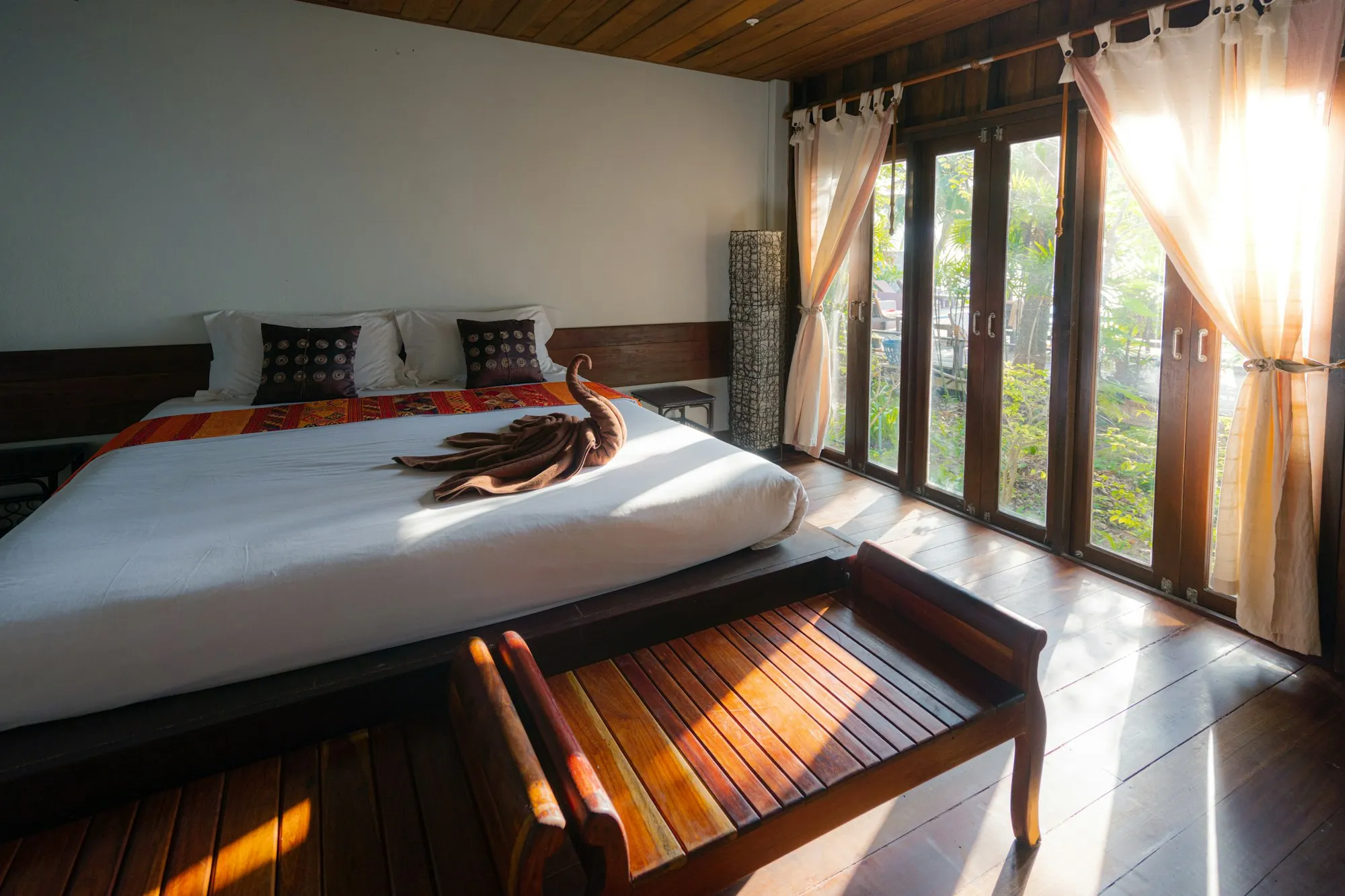A bedroom with wooden floors and tall doors open to the garden